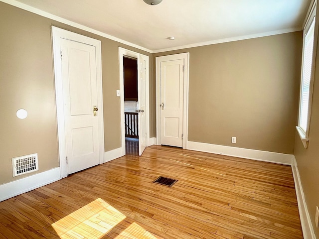 unfurnished bedroom featuring multiple windows, light hardwood / wood-style floors, and ornamental molding