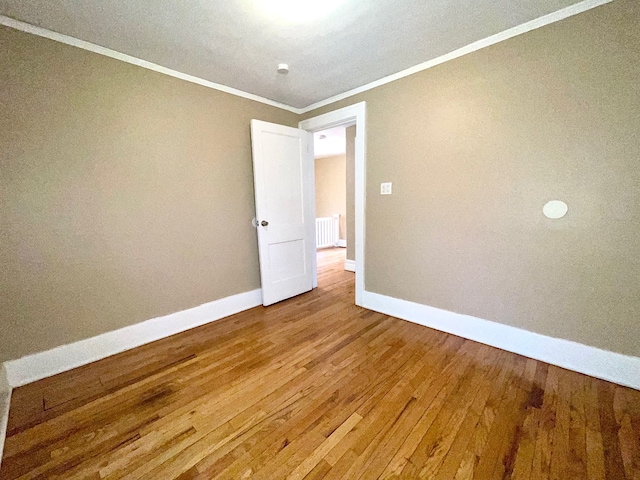 empty room featuring hardwood / wood-style floors and crown molding