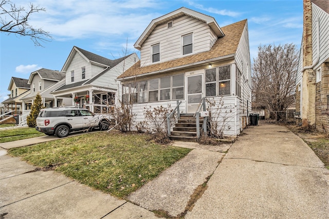 view of front facade with a sunroom and a front lawn