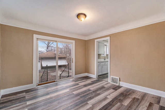 spare room featuring crown molding and dark hardwood / wood-style floors