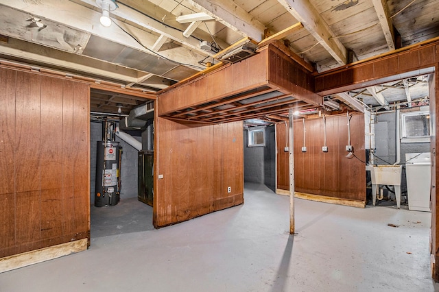 basement featuring sink, gas water heater, washer / dryer, and wooden walls