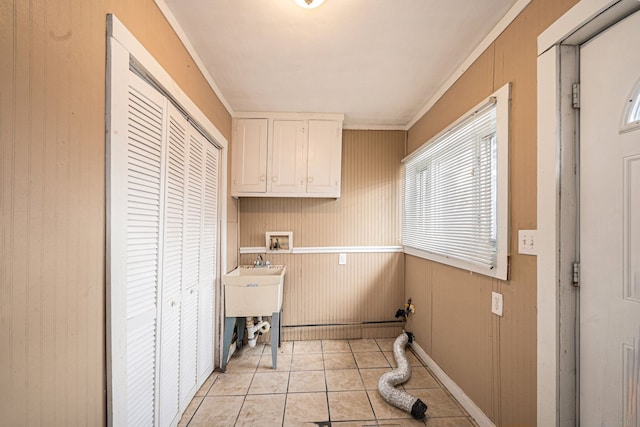 clothes washing area featuring cabinets, washer hookup, ornamental molding, wooden walls, and light tile patterned flooring