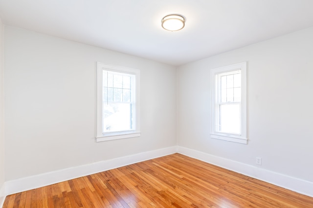 unfurnished room with hardwood / wood-style flooring and a healthy amount of sunlight