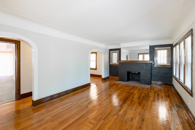 unfurnished living room featuring a fireplace, a wealth of natural light, and hardwood / wood-style floors