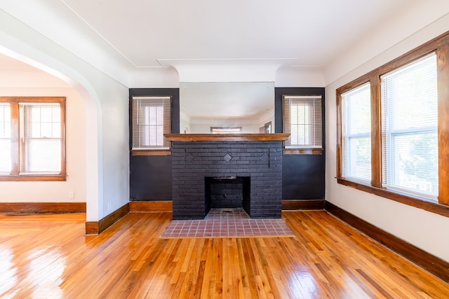 unfurnished living room with hardwood / wood-style floors and a brick fireplace