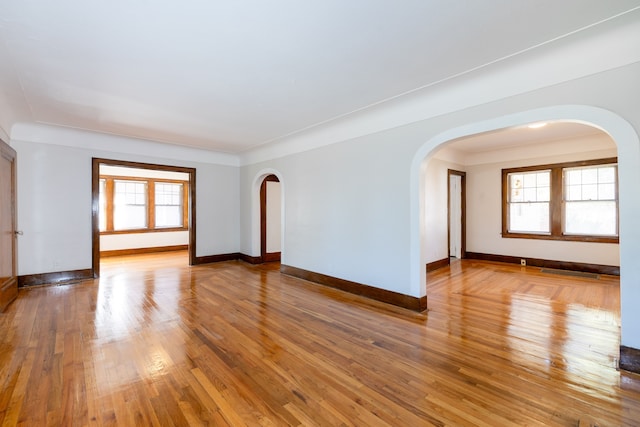 unfurnished room with wood-type flooring, ornamental molding, and a healthy amount of sunlight