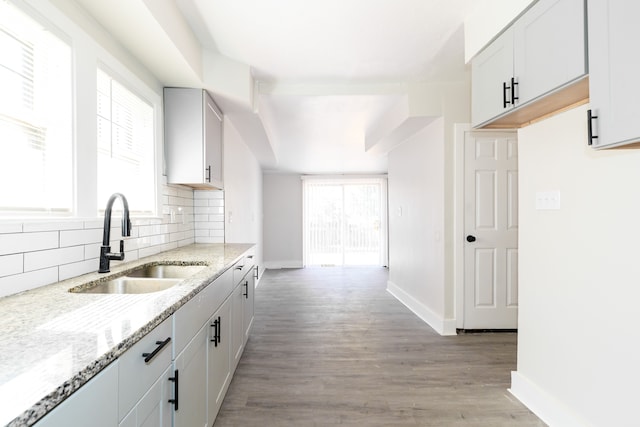 kitchen featuring backsplash, light stone counters, a healthy amount of sunlight, and light wood-type flooring