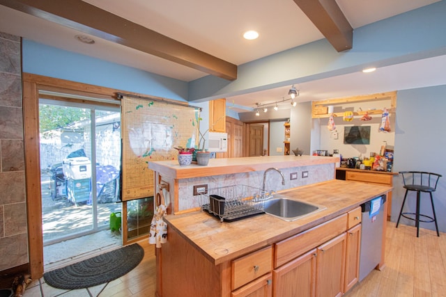 kitchen featuring stainless steel dishwasher, sink, light hardwood / wood-style flooring, butcher block countertops, and an island with sink