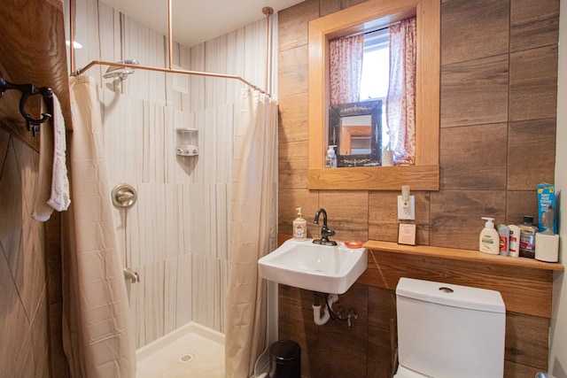 bathroom featuring toilet, tile walls, sink, and walk in shower