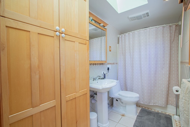 bathroom with sink, a skylight, tile patterned flooring, toilet, and curtained shower