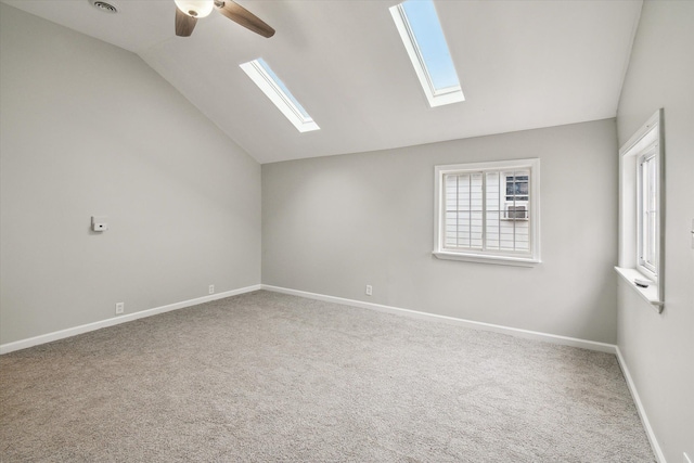 carpeted empty room with vaulted ceiling with skylight and ceiling fan