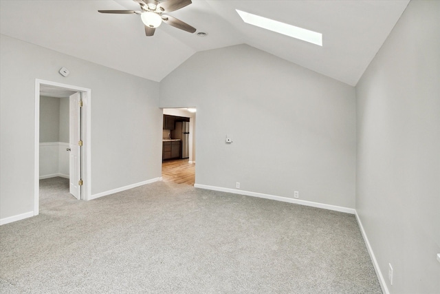 interior space featuring lofted ceiling with skylight, ceiling fan, and light carpet