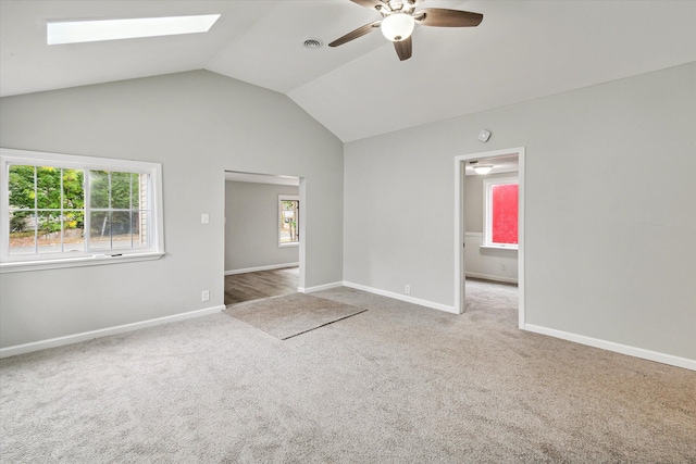 carpeted empty room featuring ceiling fan and lofted ceiling with skylight