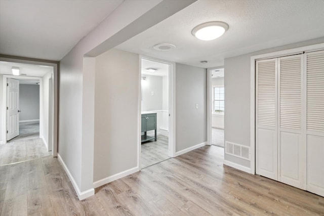 hall with light hardwood / wood-style floors and a textured ceiling