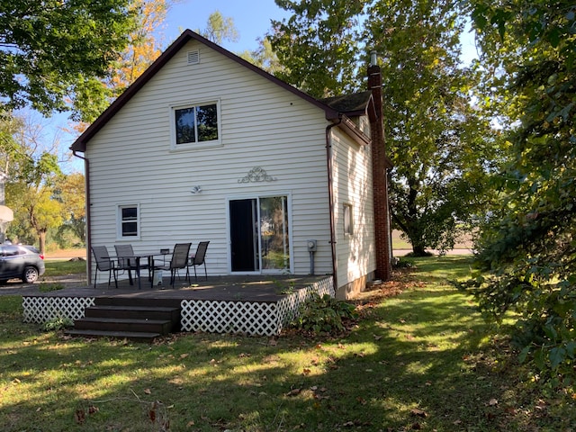 back of house featuring a lawn and a wooden deck