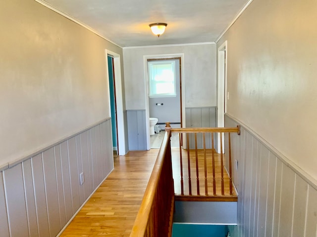 corridor with light hardwood / wood-style floors, ornamental molding, and a baseboard heating unit