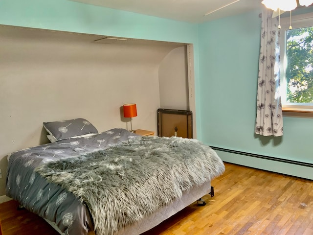 bedroom with baseboard heating, ceiling fan, and hardwood / wood-style floors