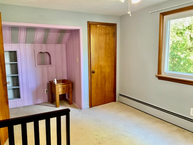 unfurnished bedroom with light carpet and a baseboard heating unit