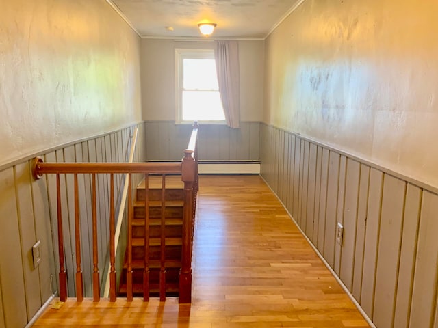 stairway featuring crown molding, wood-type flooring, and a baseboard heating unit