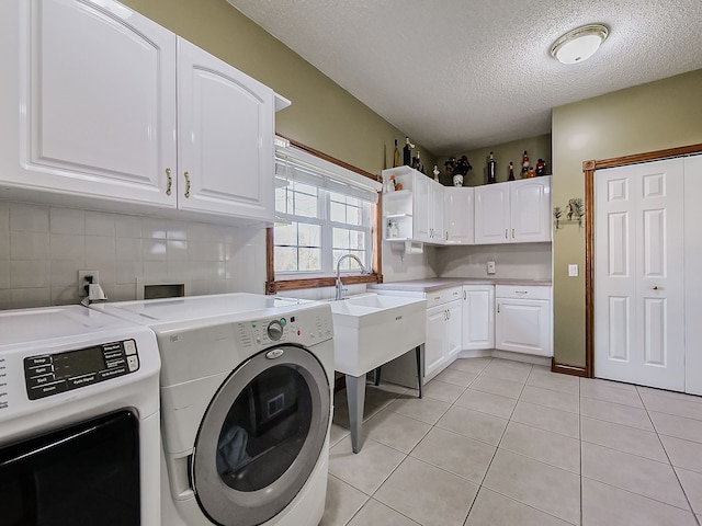 washroom with light tile patterned flooring, cabinets, independent washer and dryer, and a textured ceiling