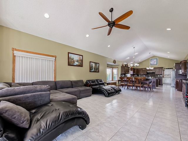 tiled living room with ceiling fan with notable chandelier and vaulted ceiling