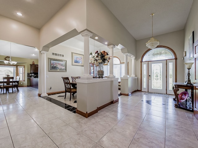 tiled entrance foyer with a wealth of natural light, a towering ceiling, and a chandelier