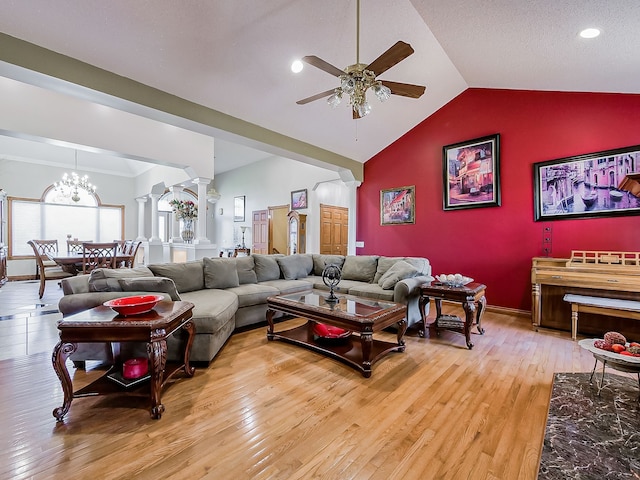 living room with ceiling fan with notable chandelier, light wood-type flooring, vaulted ceiling, and ornate columns