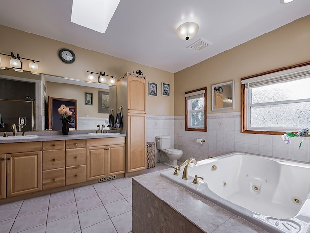 bathroom with tile patterned floors, vanity, toilet, and a skylight