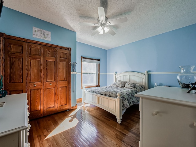 bedroom with dark hardwood / wood-style floors, ceiling fan, and a textured ceiling