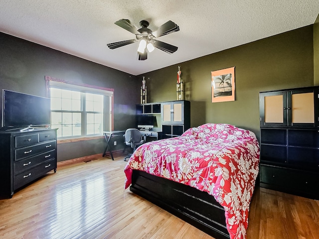 bedroom with hardwood / wood-style floors, ceiling fan, and a textured ceiling