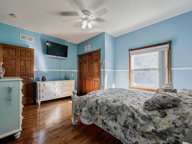 bedroom with a textured ceiling, dark hardwood / wood-style flooring, a closet, and ceiling fan