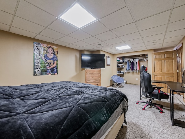 carpeted bedroom featuring a drop ceiling