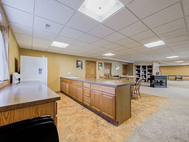 kitchen with a center island, a drop ceiling, and sink