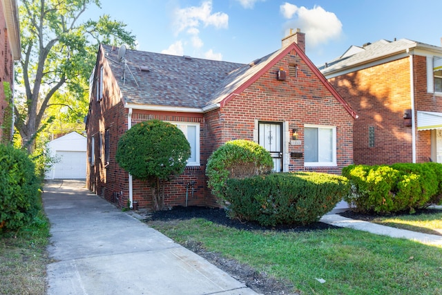 view of front of house featuring a garage, an outbuilding, and a front lawn