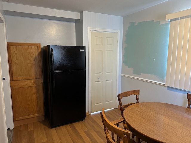 kitchen with light wood-type flooring and black fridge