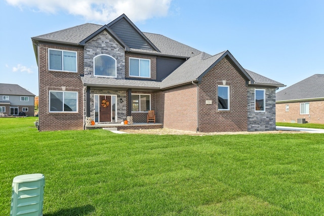 view of front facade featuring a front yard, brick siding, and a shingled roof