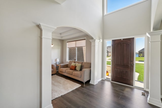 entrance foyer with a towering ceiling, decorative columns, and dark hardwood / wood-style floors