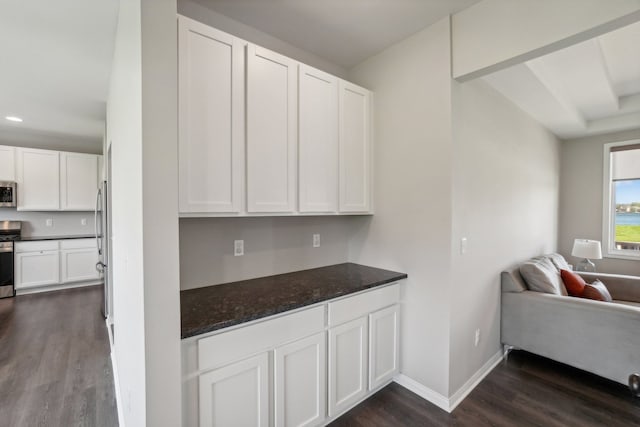 kitchen with baseboards, stainless steel appliances, dark wood-type flooring, white cabinetry, and open floor plan