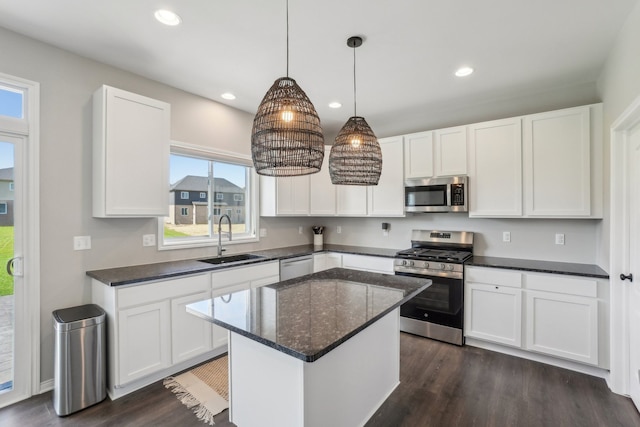 kitchen with sink, appliances with stainless steel finishes, a center island, white cabinets, and decorative light fixtures