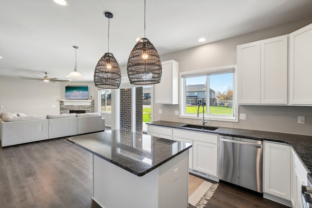 kitchen featuring sink, white cabinetry, hanging light fixtures, a fireplace, and stainless steel dishwasher