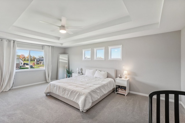 carpeted bedroom featuring ceiling fan and a tray ceiling