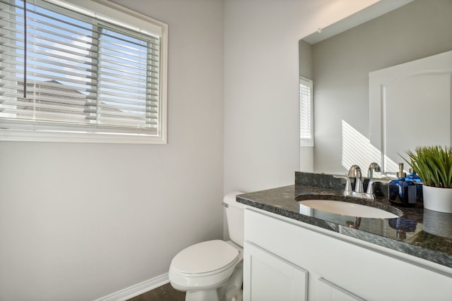 bathroom with baseboards, toilet, and vanity