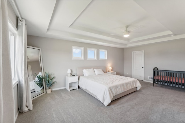 bedroom with carpet flooring, a raised ceiling, and baseboards