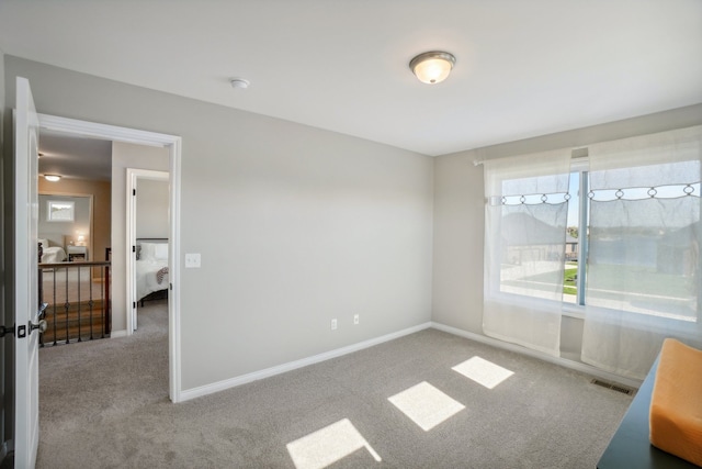 carpeted spare room with visible vents and baseboards