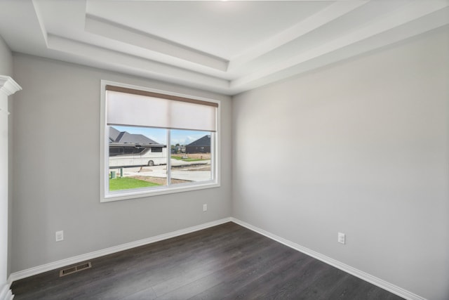 spare room featuring visible vents, a raised ceiling, dark wood-type flooring, and baseboards