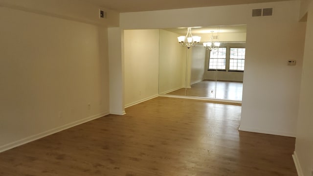 unfurnished room featuring a chandelier and hardwood / wood-style flooring