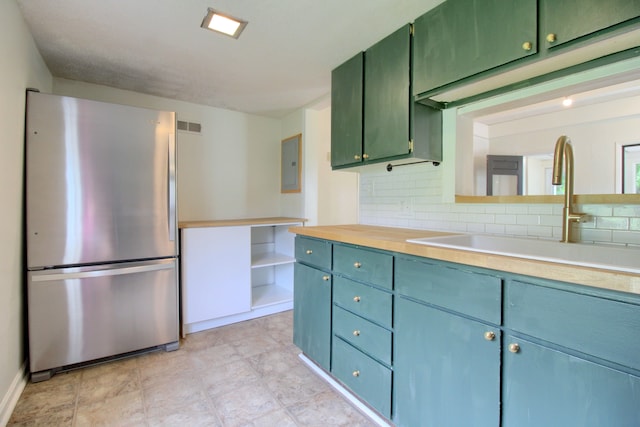 kitchen with backsplash, stainless steel fridge, sink, and electric panel