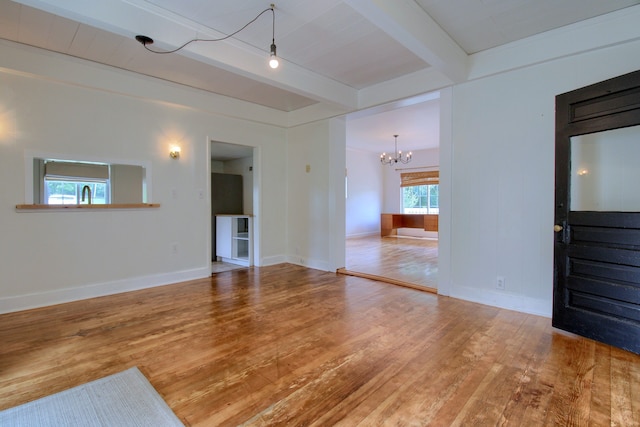 unfurnished living room featuring beamed ceiling, hardwood / wood-style flooring, and a chandelier