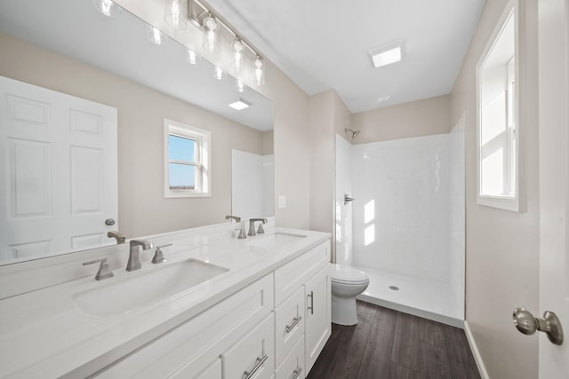 bathroom with hardwood / wood-style floors, vanity, a tile shower, and toilet