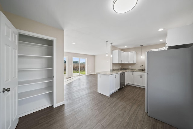 kitchen with kitchen peninsula, dark hardwood / wood-style flooring, decorative light fixtures, white cabinetry, and fridge